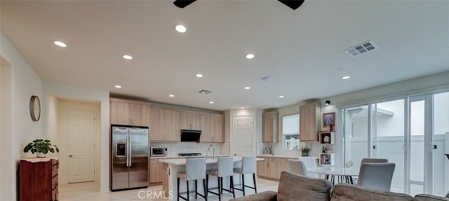 kitchen with range hood, appliances with stainless steel finishes, a wealth of natural light, and an island with sink