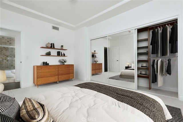 bedroom featuring connected bathroom, light carpet, and a closet