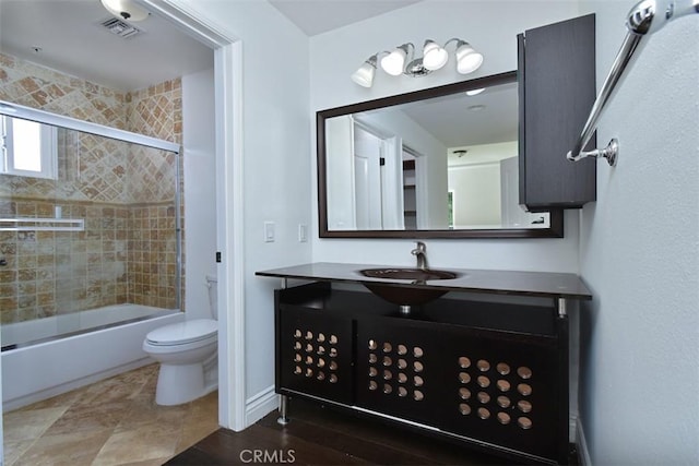 full bathroom featuring toilet, combined bath / shower with glass door, and vanity