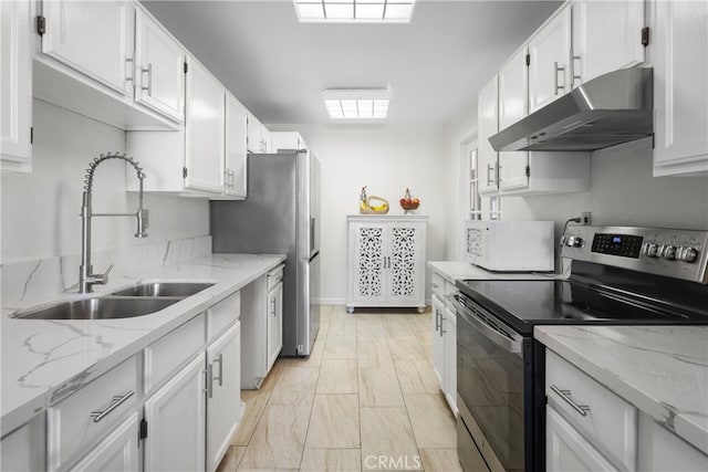 kitchen with white cabinets, light stone counters, sink, and appliances with stainless steel finishes