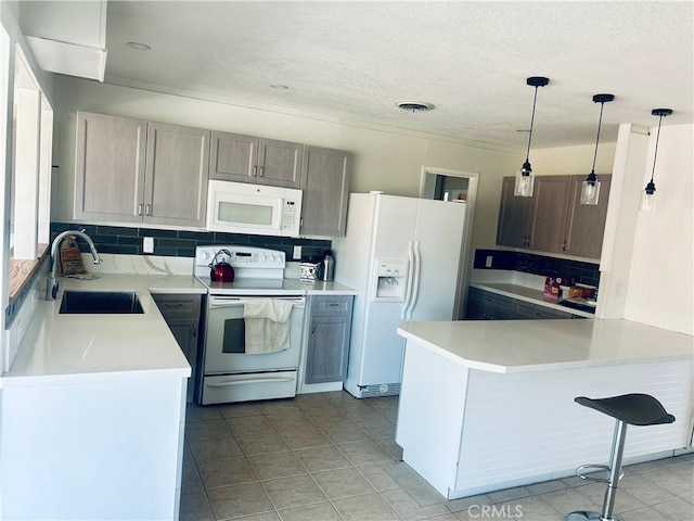 kitchen featuring hanging light fixtures, kitchen peninsula, sink, white appliances, and decorative backsplash