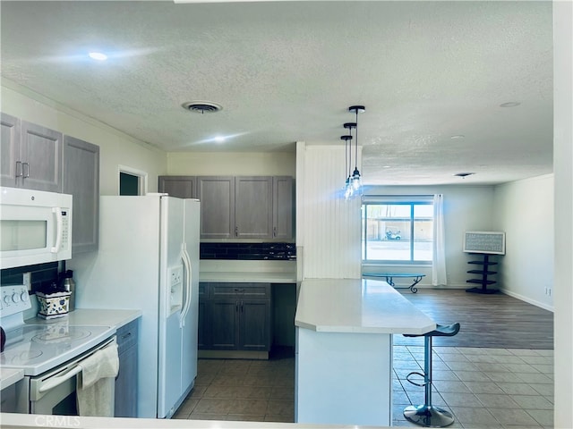 kitchen with wood-type flooring, hanging light fixtures, decorative backsplash, a kitchen breakfast bar, and white appliances