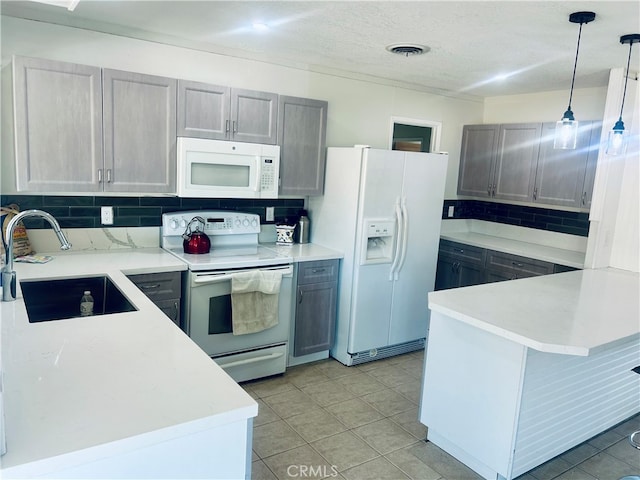 kitchen with white appliances, kitchen peninsula, gray cabinets, decorative light fixtures, and sink