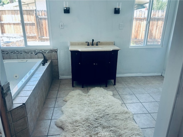 bathroom featuring tiled tub, vanity, and tile patterned floors