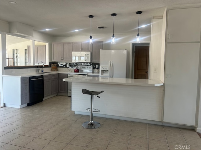 kitchen featuring hanging light fixtures, kitchen peninsula, white appliances, and a breakfast bar