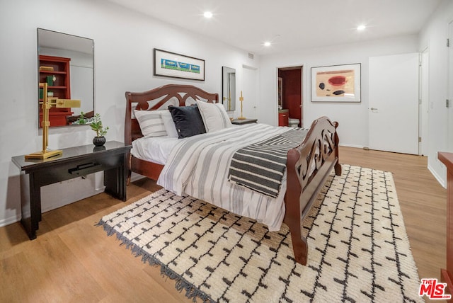 bedroom featuring light hardwood / wood-style floors and ensuite bath