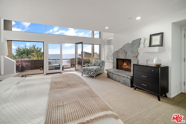 bedroom with access to exterior, a fireplace, a water view, and light colored carpet