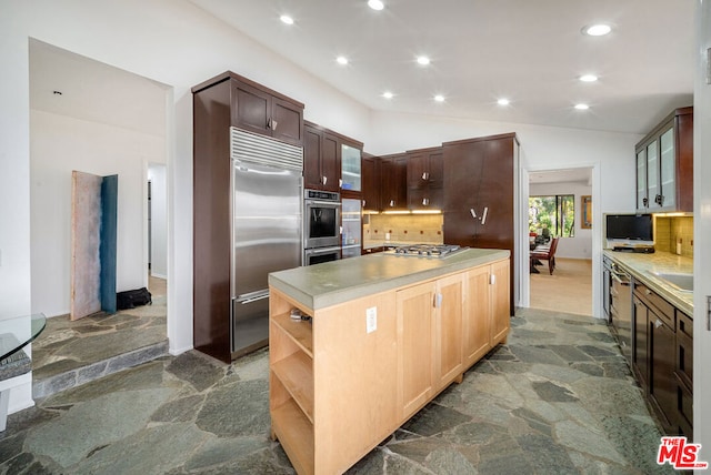 kitchen featuring vaulted ceiling, appliances with stainless steel finishes, decorative backsplash, and a center island