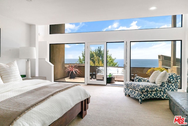 bedroom featuring a water view, light carpet, and access to outside