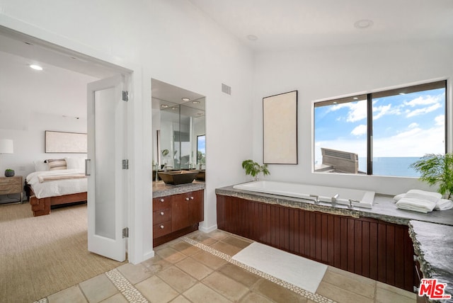 bathroom featuring a water view, a bathtub, lofted ceiling, and vanity