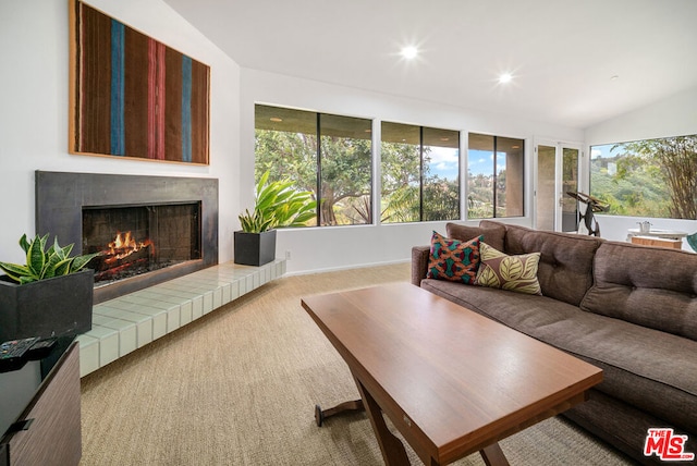 carpeted living room with lofted ceiling and a tile fireplace