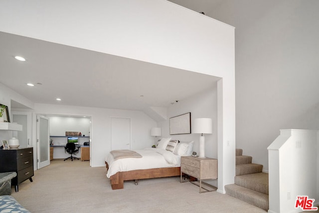 bedroom with light colored carpet and built in desk