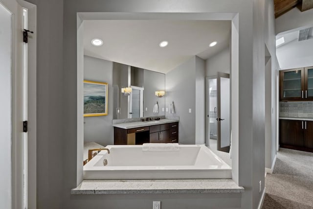 bathroom featuring vanity, a bathing tub, and backsplash