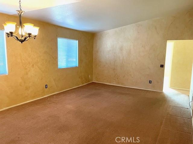 unfurnished room with carpet and a chandelier