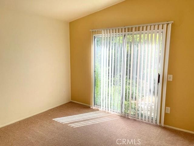 carpeted empty room with vaulted ceiling and a wealth of natural light