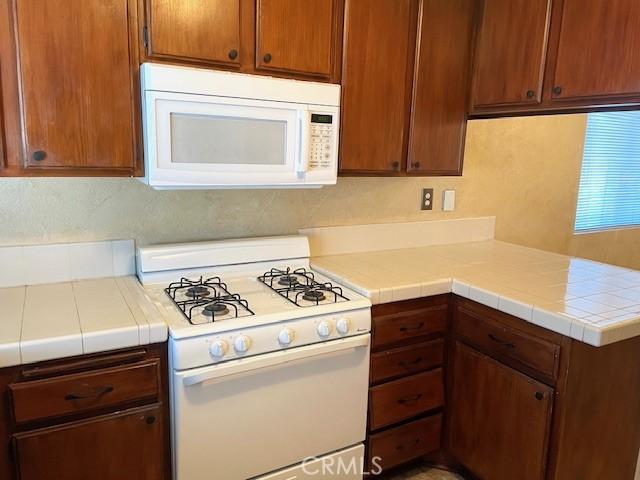 kitchen with tile counters, white appliances, and kitchen peninsula