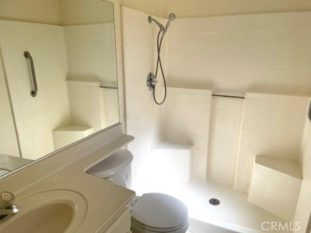 bathroom featuring tiled shower, toilet, and sink