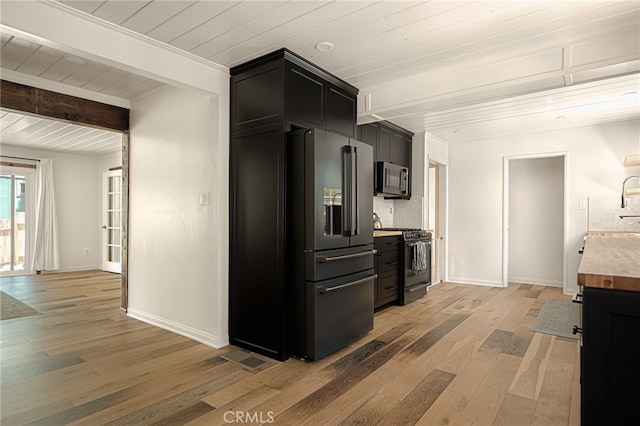 kitchen featuring butcher block countertops, hardwood / wood-style floors, beamed ceiling, and stainless steel appliances