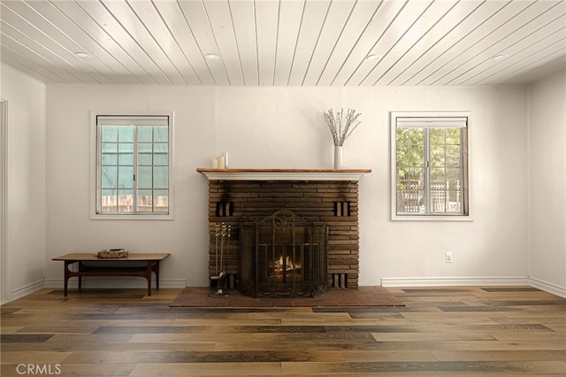 living room featuring wood ceiling, wood-type flooring, and a stone fireplace