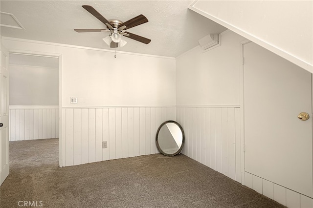 empty room with wood walls, a textured ceiling, lofted ceiling, ceiling fan, and carpet