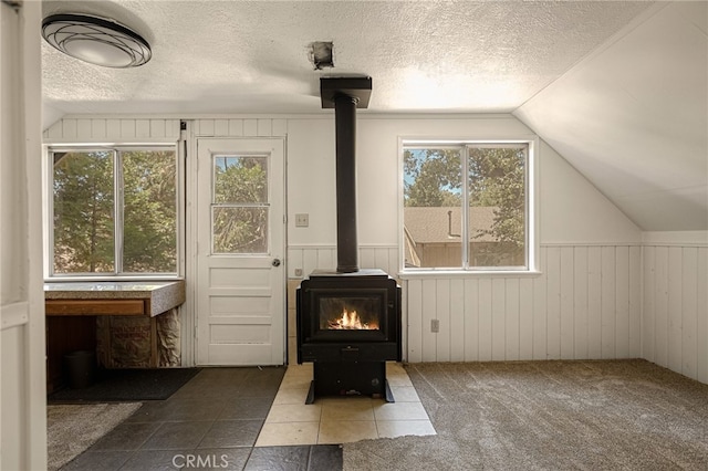 interior space featuring a textured ceiling, a healthy amount of sunlight, and a wood stove