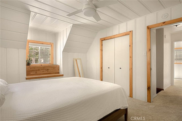 bedroom featuring ceiling fan, a closet, wood walls, and carpet