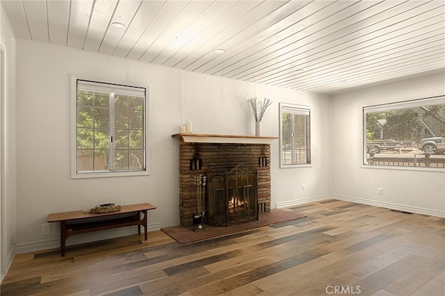 living room featuring wooden ceiling, wood-type flooring, a fireplace, and plenty of natural light