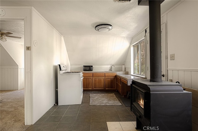 bathroom with a wood stove, a textured ceiling, lofted ceiling, ceiling fan, and sink