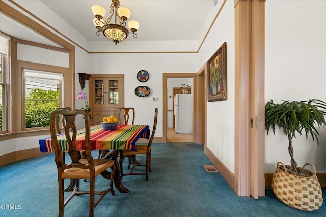 dining area with an inviting chandelier and dark colored carpet