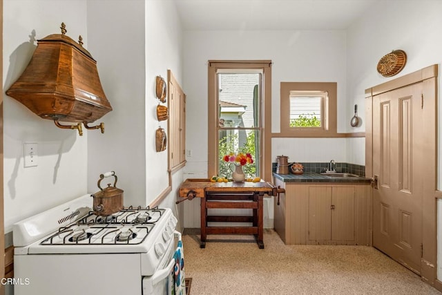 kitchen featuring sink, white gas stove, and custom range hood