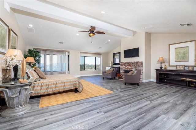 bedroom featuring a fireplace, lofted ceiling with beams, light hardwood / wood-style flooring, and ceiling fan