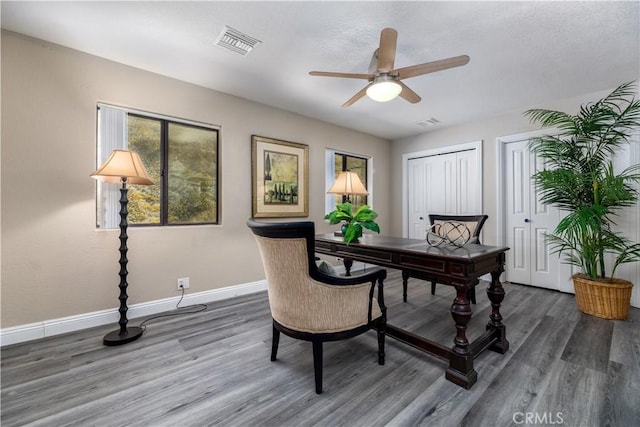 home office with ceiling fan and dark hardwood / wood-style flooring