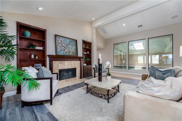 living room featuring vaulted ceiling with beams, dark hardwood / wood-style floors, and a tile fireplace