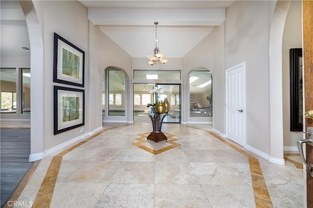 foyer entrance featuring beam ceiling, high vaulted ceiling, and a chandelier