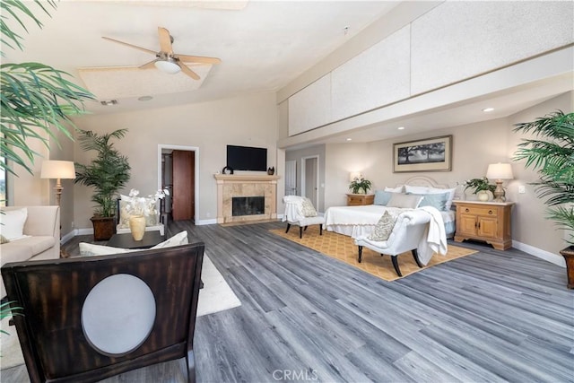 bedroom with a tile fireplace, ceiling fan, dark hardwood / wood-style flooring, and high vaulted ceiling