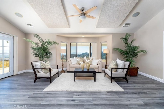 living room with a textured ceiling, dark hardwood / wood-style flooring, and ceiling fan