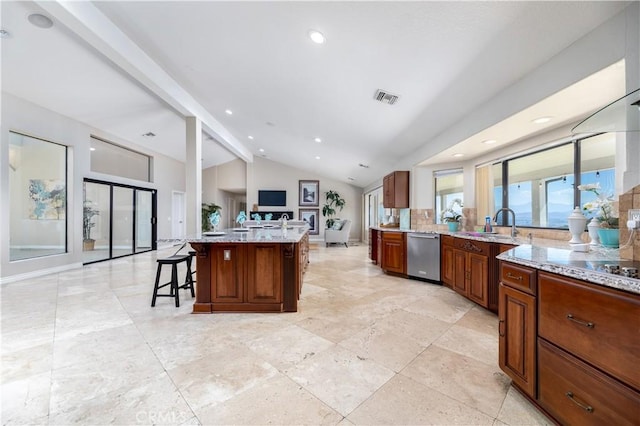 kitchen featuring dishwasher, a center island with sink, a kitchen breakfast bar, vaulted ceiling with beams, and light stone countertops