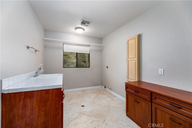 clothes washing area featuring hookup for an electric dryer, cabinets, sink, and hookup for a washing machine