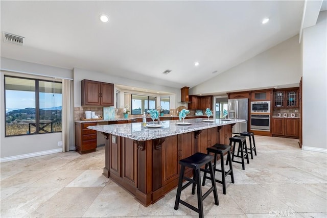 kitchen with plenty of natural light, decorative backsplash, appliances with stainless steel finishes, and vaulted ceiling