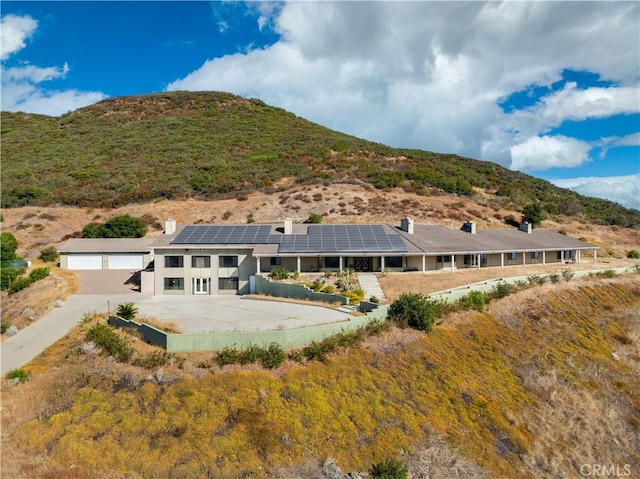 rear view of house featuring a mountain view, solar panels, and a garage