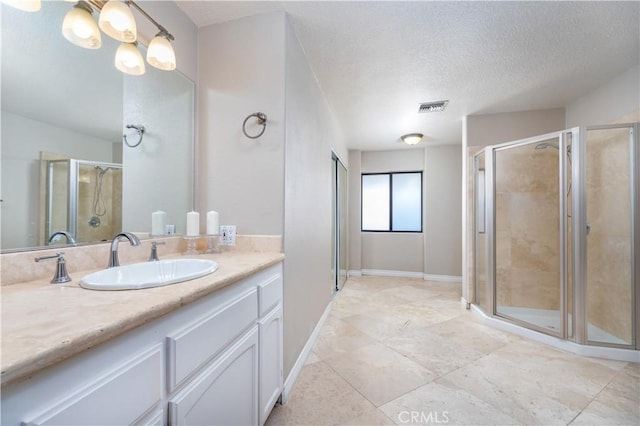 bathroom with tile patterned floors, vanity, a shower with door, and a textured ceiling