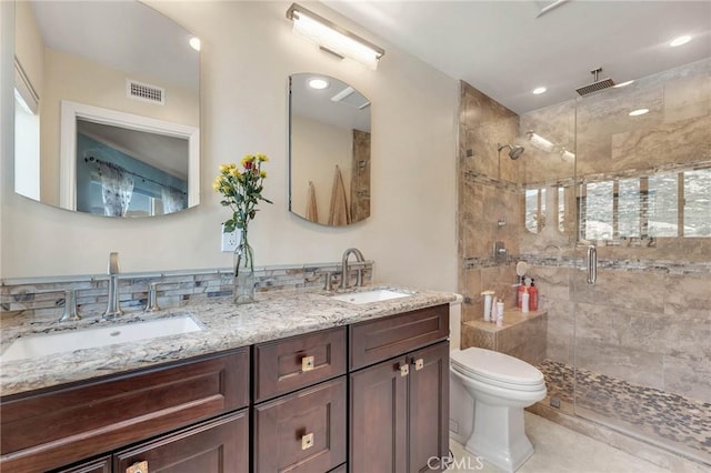 bathroom featuring vanity, a shower with shower door, and toilet