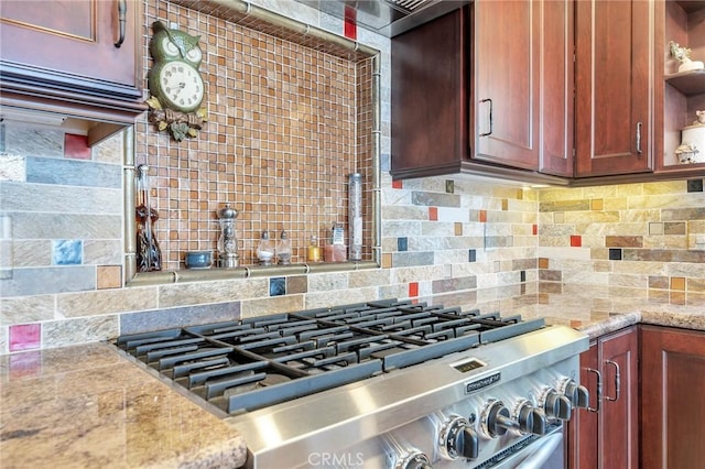 kitchen featuring decorative backsplash, light stone countertops, and stainless steel range oven