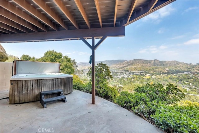 view of patio with a mountain view and a hot tub