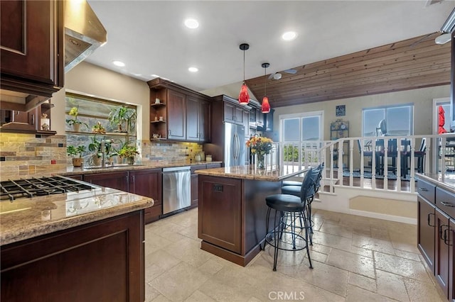 kitchen featuring a center island, stainless steel appliances, light stone counters, and hanging light fixtures