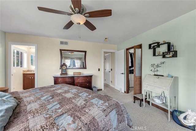 bedroom featuring ensuite bath, ceiling fan, light colored carpet, a walk in closet, and a closet