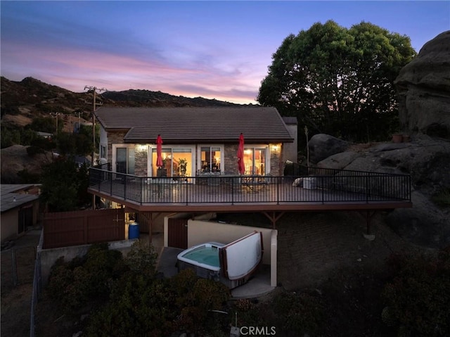 back house at dusk featuring a hot tub