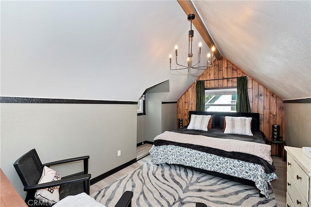 bedroom featuring a textured ceiling, wooden walls, light wood-type flooring, and lofted ceiling with beams