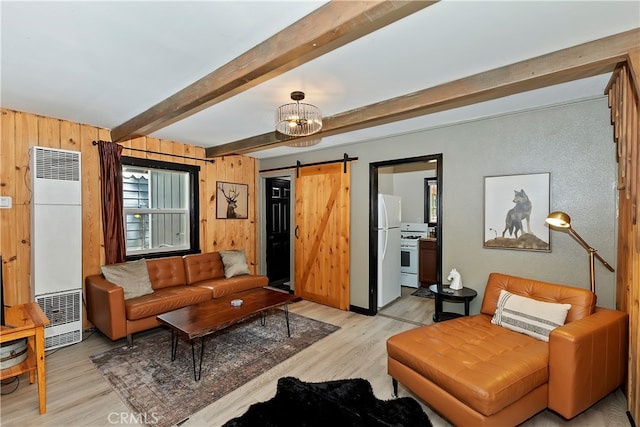 living room with beam ceiling, wooden walls, light hardwood / wood-style flooring, a notable chandelier, and a barn door