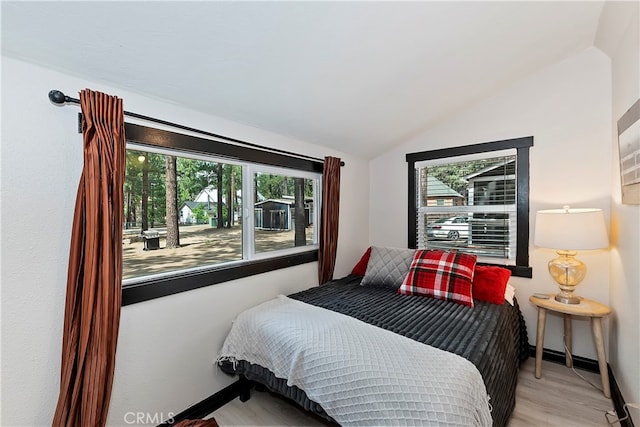 bedroom with lofted ceiling, multiple windows, and light hardwood / wood-style floors